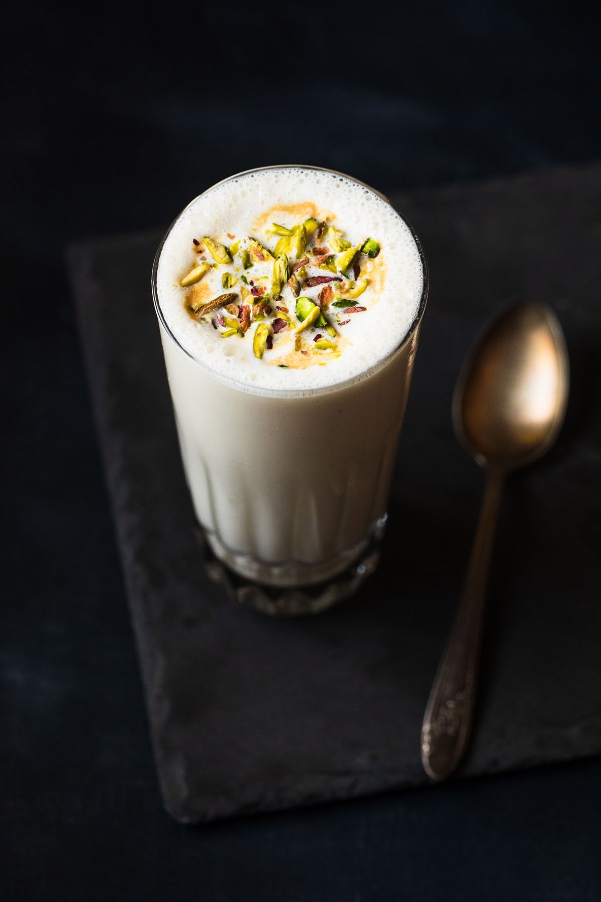 vanilla milkshake served in a glass. topped with chopped pistachios.