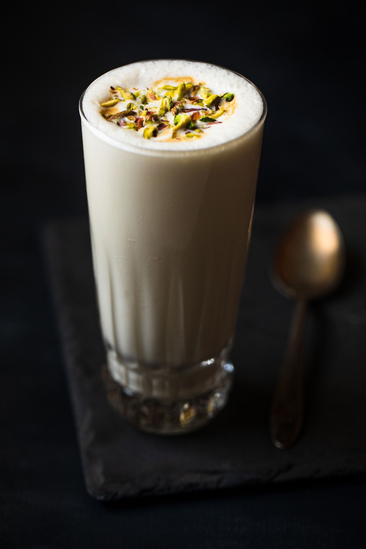 vanilla milkshake served in a glass. topped with chopped pistachios.