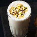 vanilla milkshake served in a glass. topped with chopped pistachios.