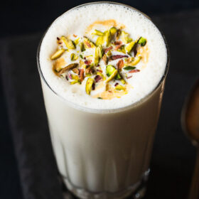 vanilla milkshake served in a glass. topped with chopped pistachios.