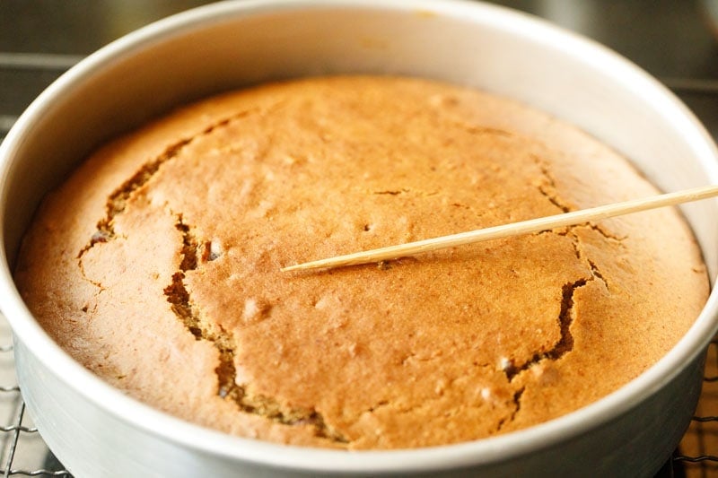 date and walnut cake being checked with a bamboo skewer.