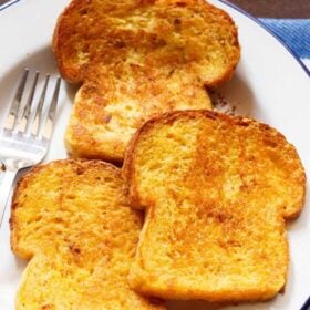 closeup shot of three french toast served on a white plate with a fork by the side with text layovers.