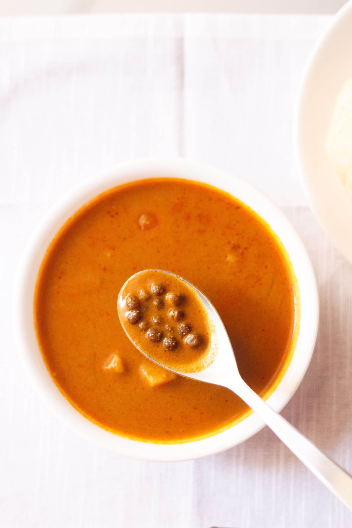 kala vatana usal in a spoon on top of bowl filled with the curry.