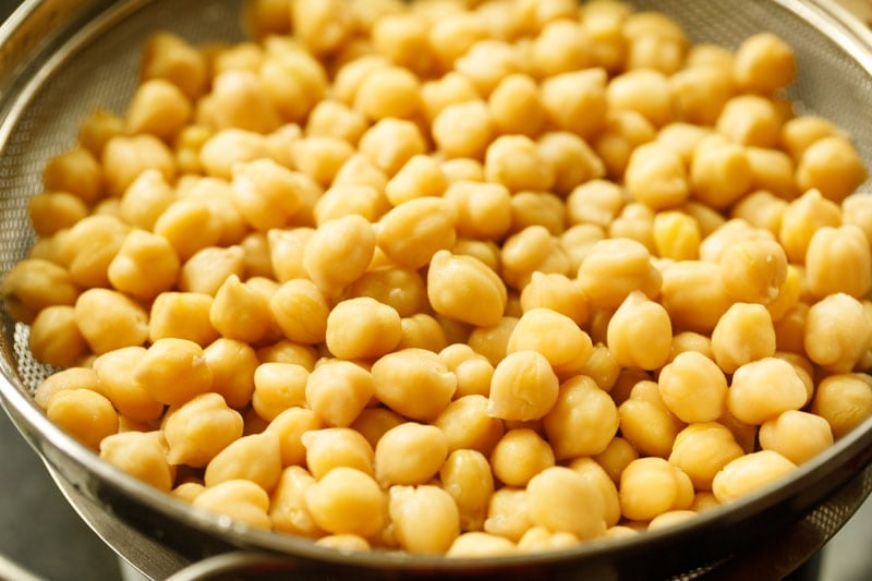 straining cooked chickpeas using a mesh strainer. 