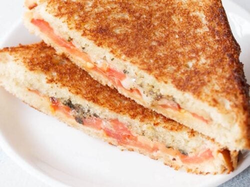 tomato sandwich served on a white plate on a white table.