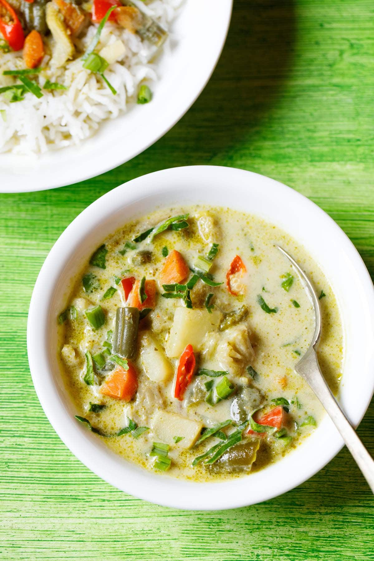 thai green curry in white bowl with a spoon inside the bowl.