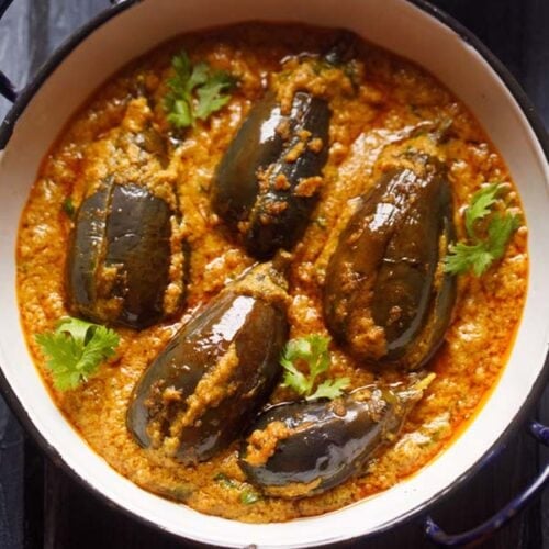 close up shot of bharli vangi or stuffed brinjal in a white dish.