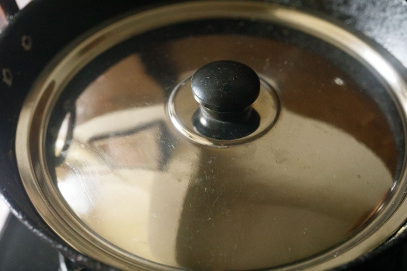 pan covered with lid to cook stuffed brinjal.