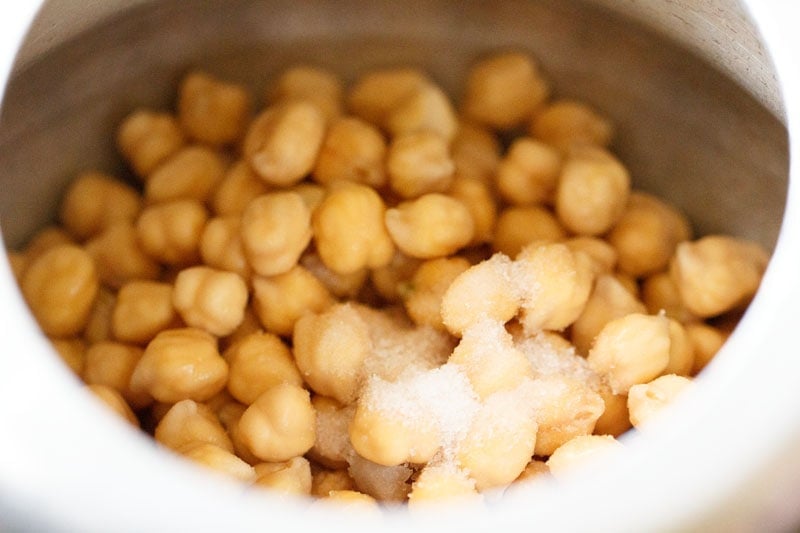 drained chickpeas added with salt in a pressure cooker for chickpea curry recipe. 