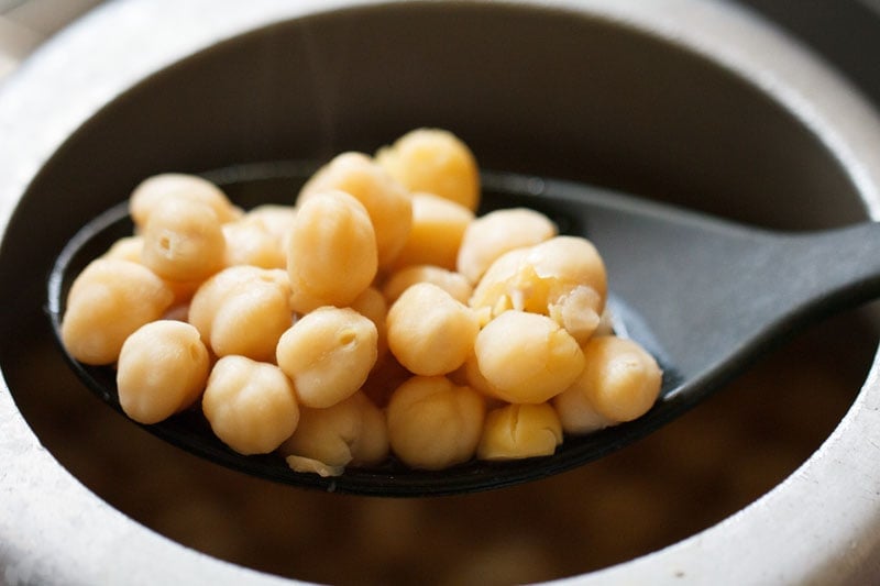 pressure cooked chickpeas in a ladle.