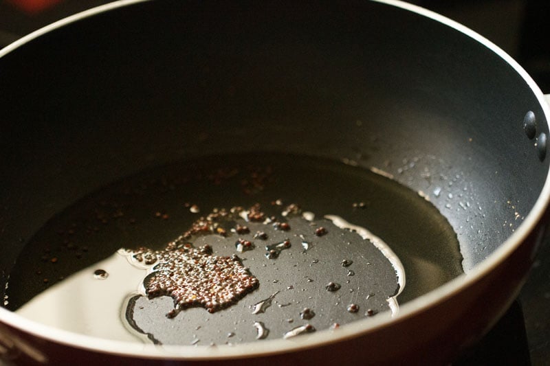 mustard seeds added to hot oil in pan. 