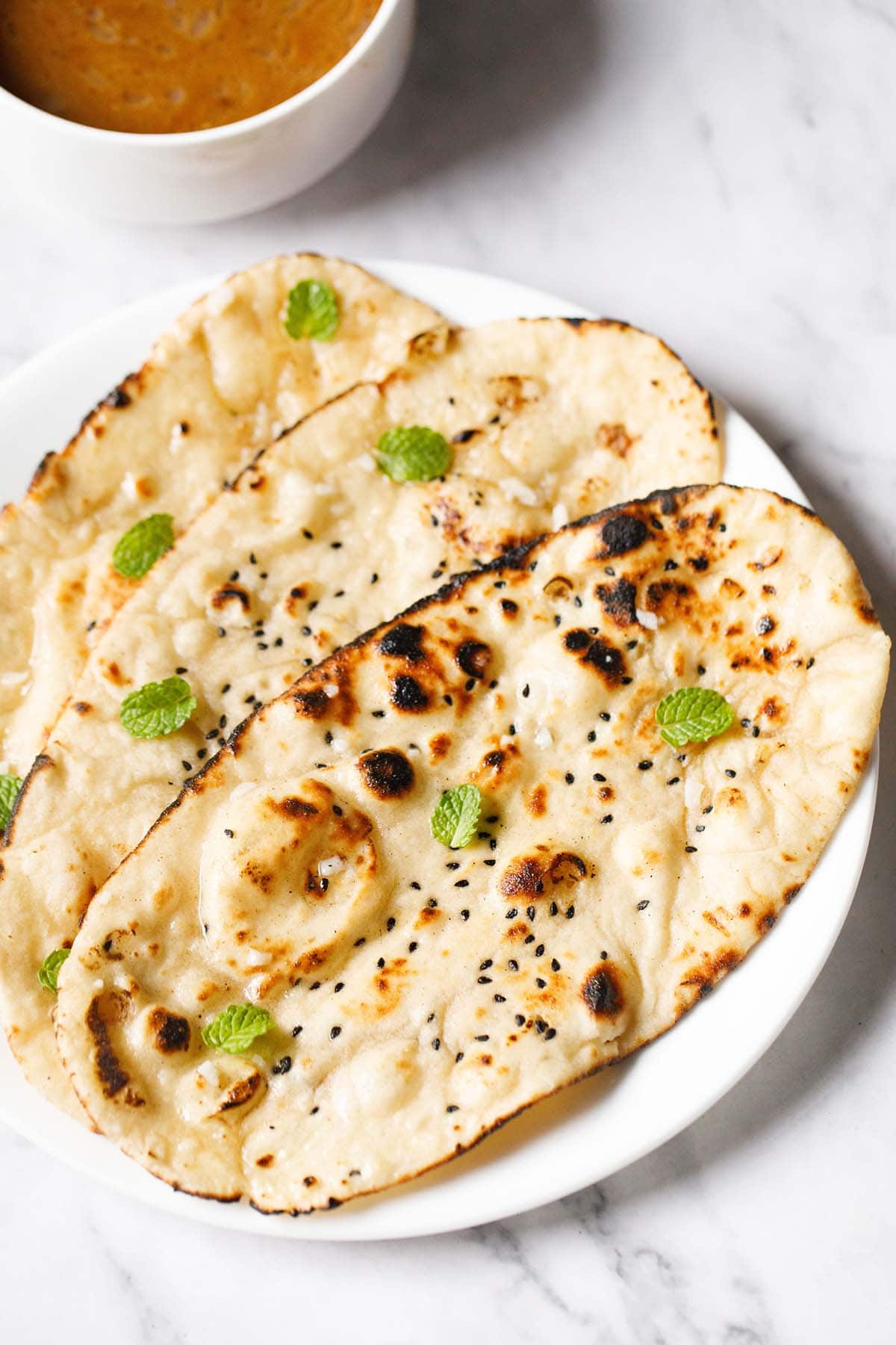 three garlic naan on a white plate.