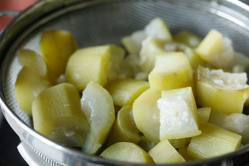 cooked lauki in a mesh strainer.