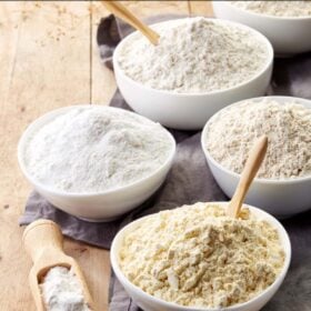 white bowls filled with various flours on wooden table.