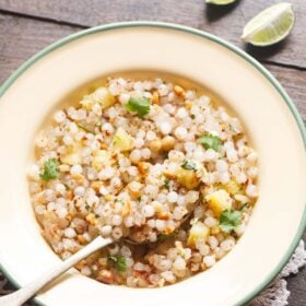 sabudana khichdi served in a green rimmed cream colored plate with a brass spoon and text layovers.