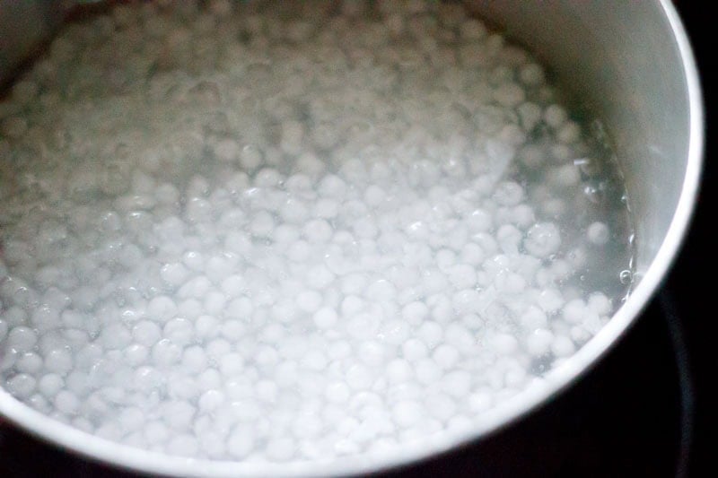 Sabudana getting cooked in water in a pan.