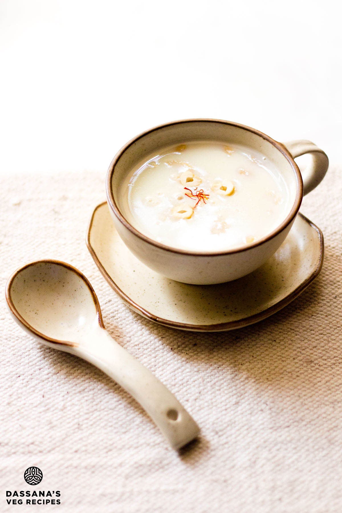 Sabudana kheer served in a ceramic cup on a ceramic plate with a spoon kept on the left side.