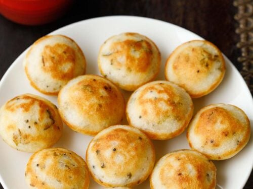 appe or paddu on a plate with coconut chutney in red bowl on top.