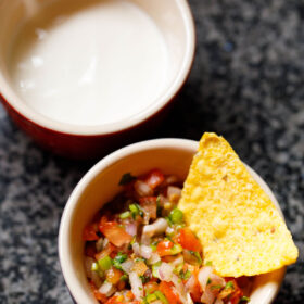 salsa fresca in a bowl with a nacho chip in it.