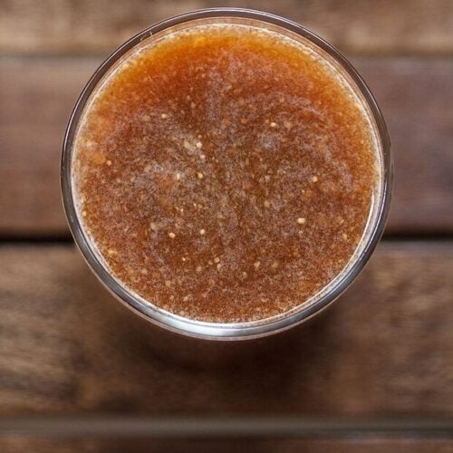 top shot of wood apple juice in a glass on a wooden tray.