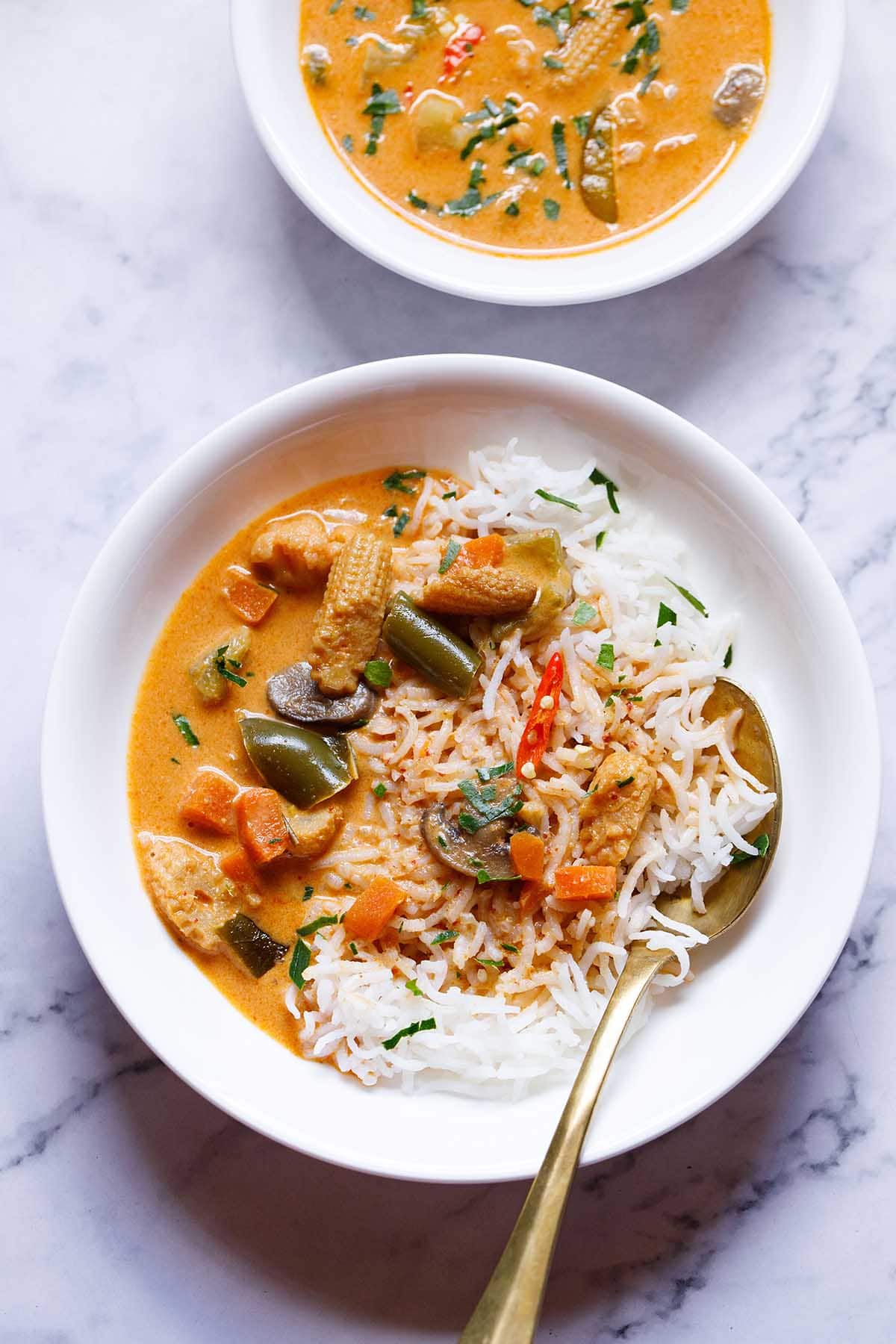 panang curry on a bed of rice with spoon in a white plate.