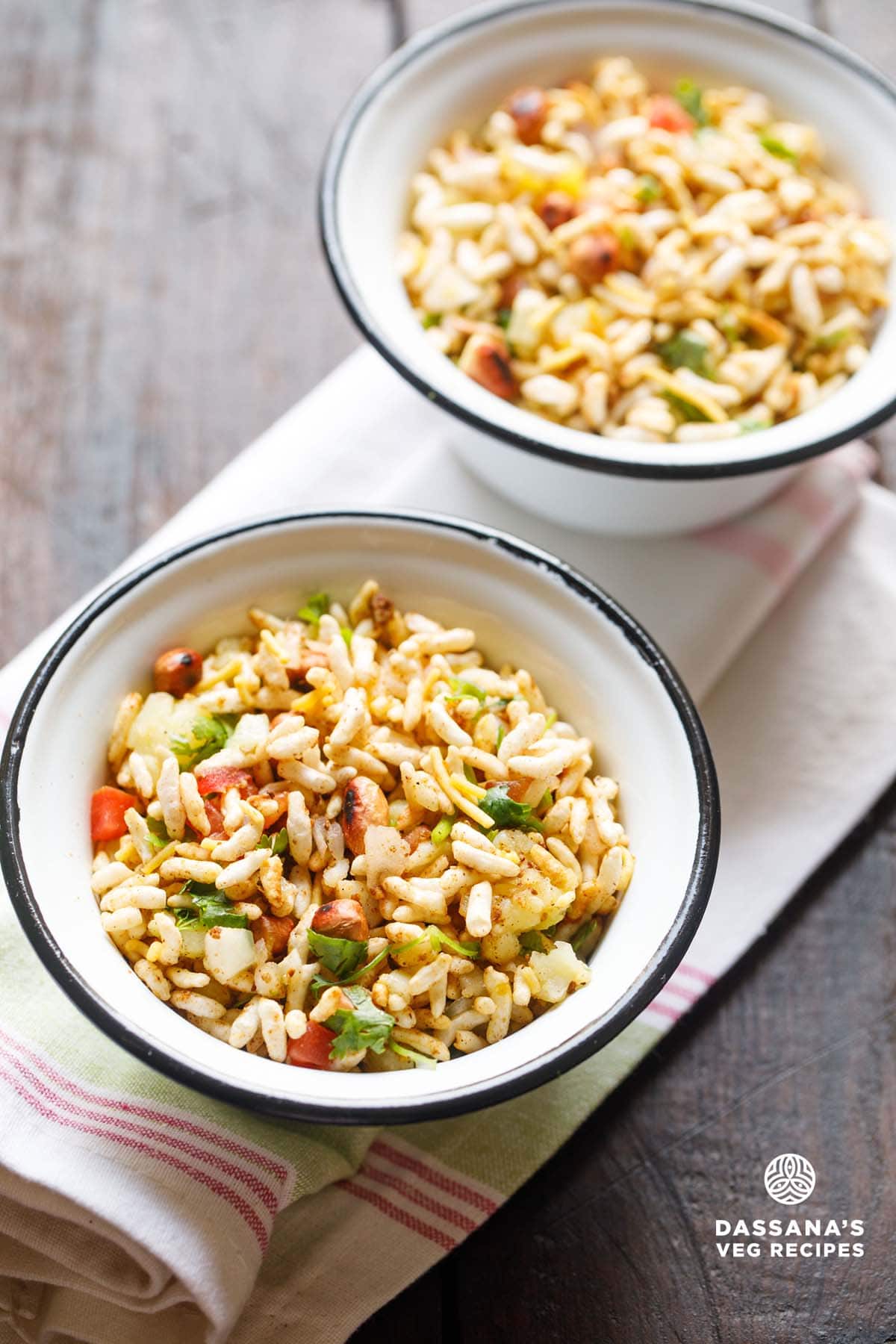 jhal muri in two black rimmed white bowls placed on a white napkin.