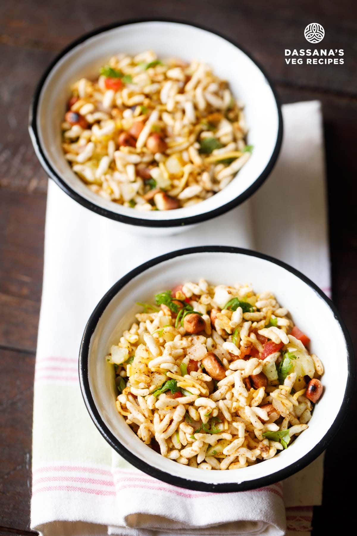 jhalmuri in two black rimmed white bowls placed on a white napkin.