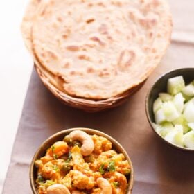 vegetable curry served in a bowl along with a side of tandoori roti and salad.
