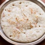 onion uttapam served on a steel plate.