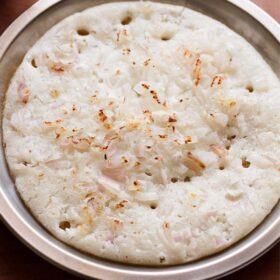 onion uttapam served on a steel plate.