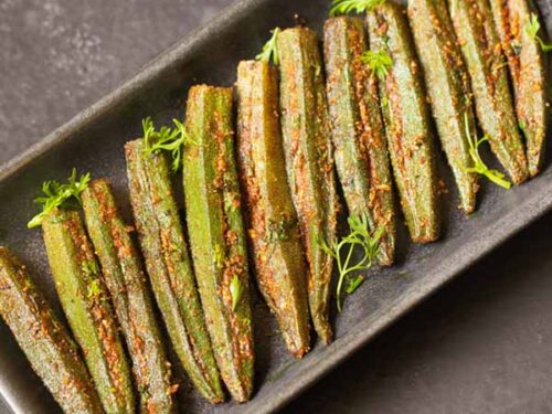bharwa bhindi garnished with coriander leaves and served on a long platter.
