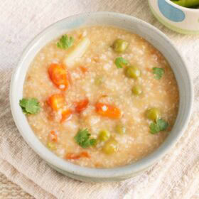 daliya khichdi in a ceramic bowl on a jute fabric.