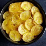banana chips or wafers served in a black bowl.