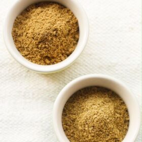 regular and roasted cumin powder in two bowls on a cream colored jute cloth with text layovers.