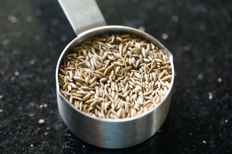 half the roasted cumin seeds in a measuring cup.