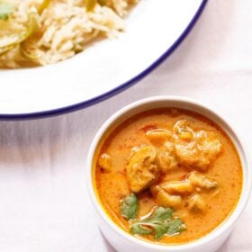 mushroom masala garnished with a coriander sprig in a white bowl placed on a white board.