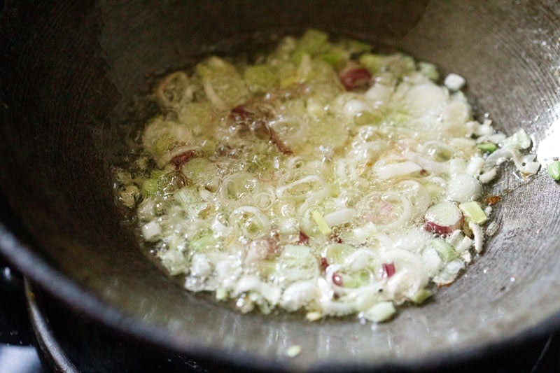 stir-frying sliced spring onion whites and finely chopped garlic in hot oil.