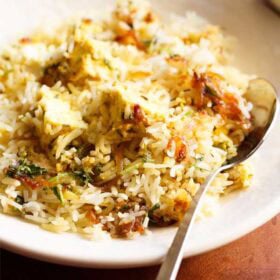 paneer biryani on a plate with a spoon on the right side.