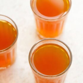 three glasses filled with sulaimani chai on a cream background.