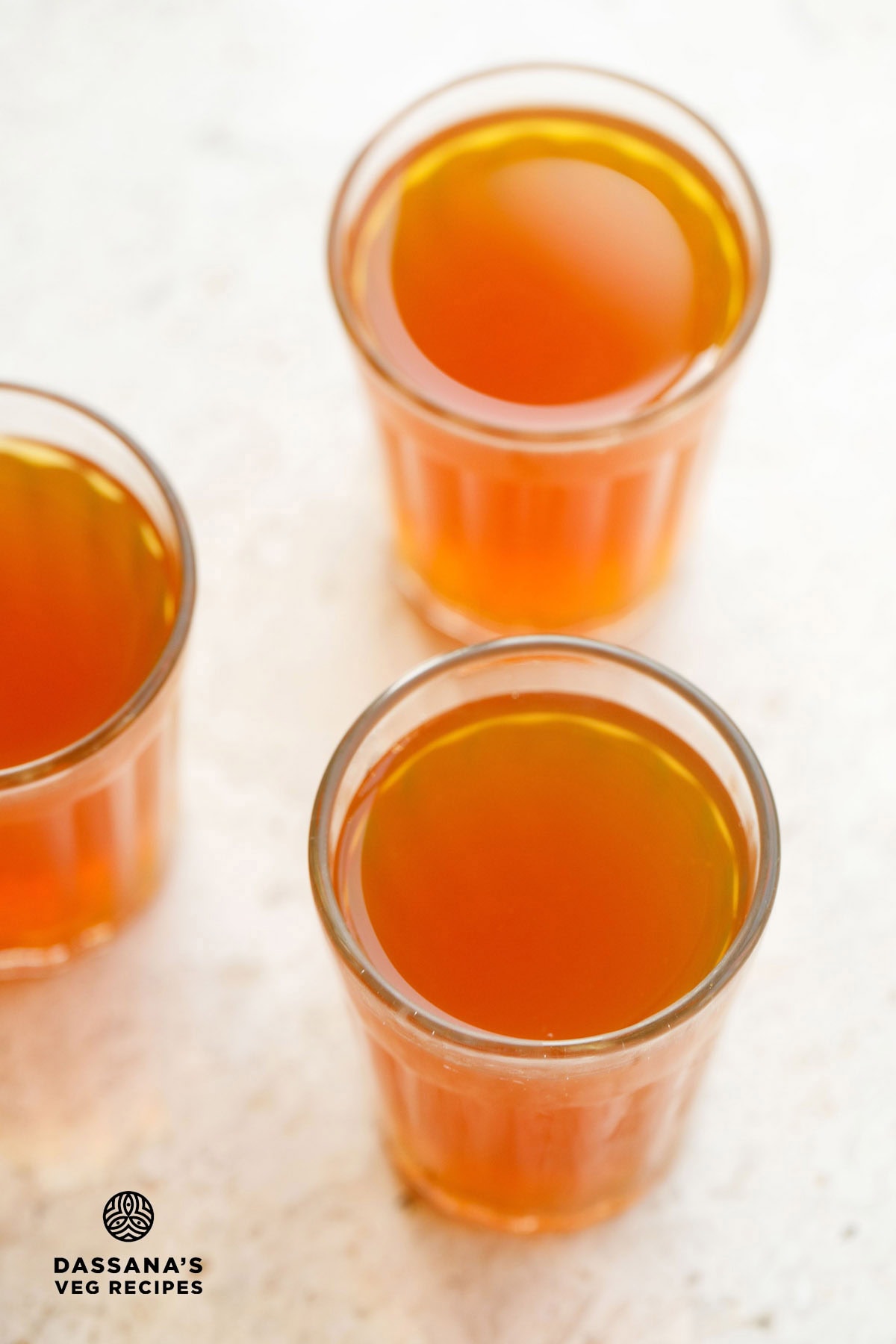three glasses filled with sulaimani chai on a cream background.