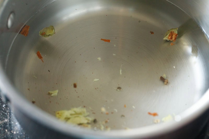 crushed whole spices and ginger added to water in a saucepan. 