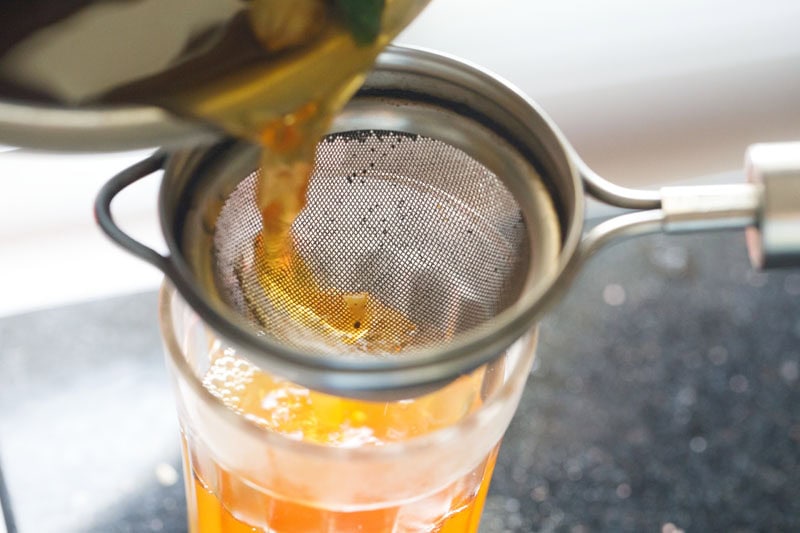 straining sulaimani chai into a glass. 