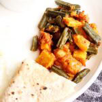 aloo bhindi served on a white plate with a folded roti.
