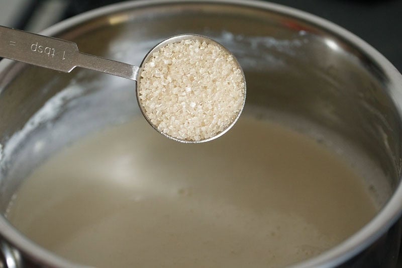 adding sugar to boiling milk. 