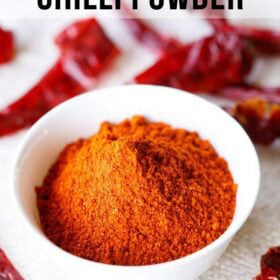 homemade red chilli powder in a white bowl with dried red chillies on top and at the bottom of the bowl on a jute cloth with text layovers.