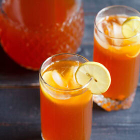iced tea with lemon, ice cubes in two glasses with a glass pitcher full of the tea kept behind.