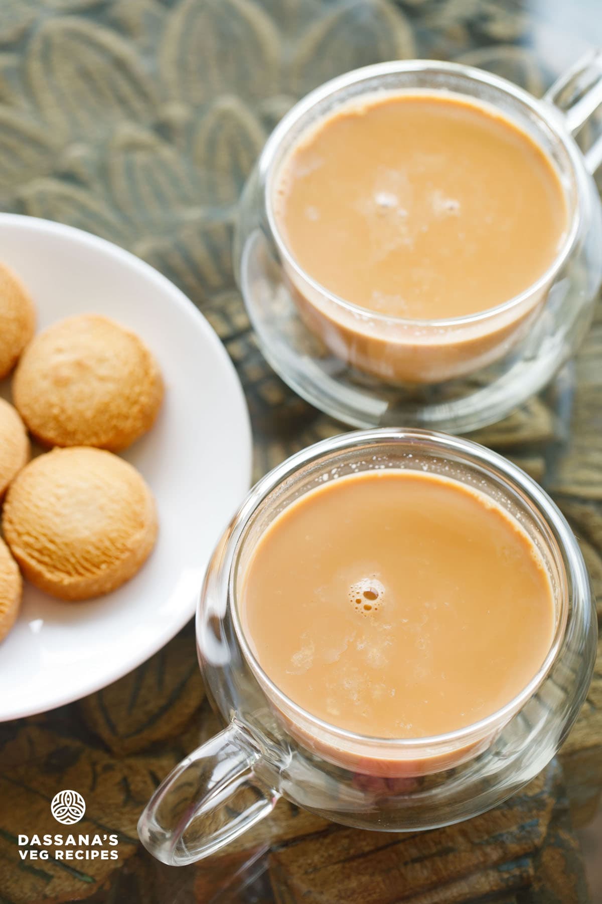 irani chai in round glass cups with a plate of osmania biscuits at the side on a wooden table.