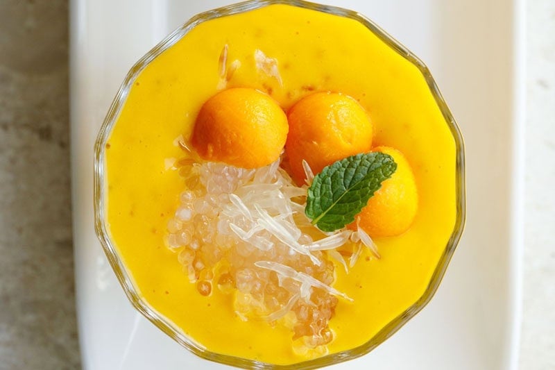 top shot of mango sago topped with sago, pomelo, mango balls, and a mint leaf.