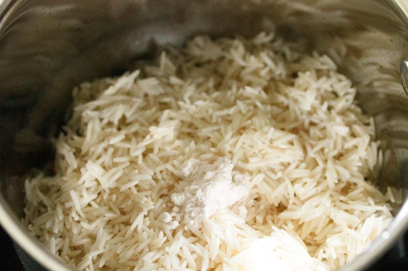 rice and salt added to whole spices for making jeera rice.