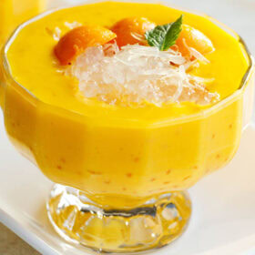 mango sago topped with sago, pomelo, and a mint leaf in a glass cup.
